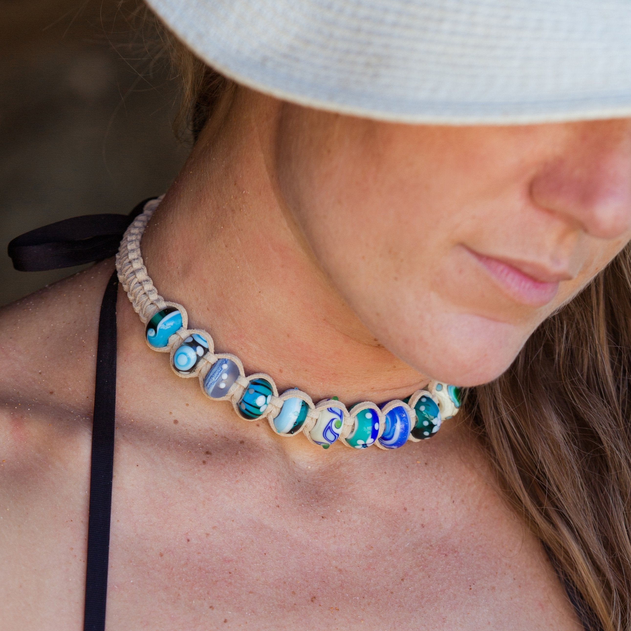 Glass travel charm choker surf style necklace worn by surfer girl.