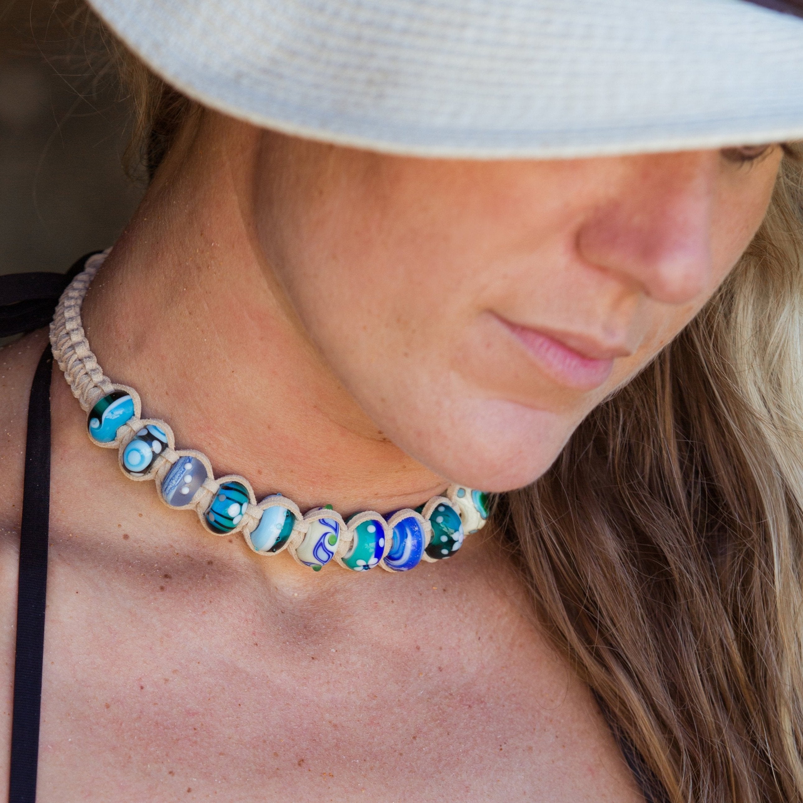 Woman in white hat wearing a beaded cord choker necklace.