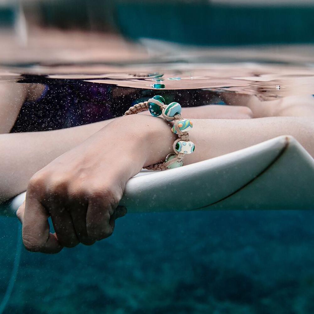 Surfer in the sea wearing a cord beaded bracelet.