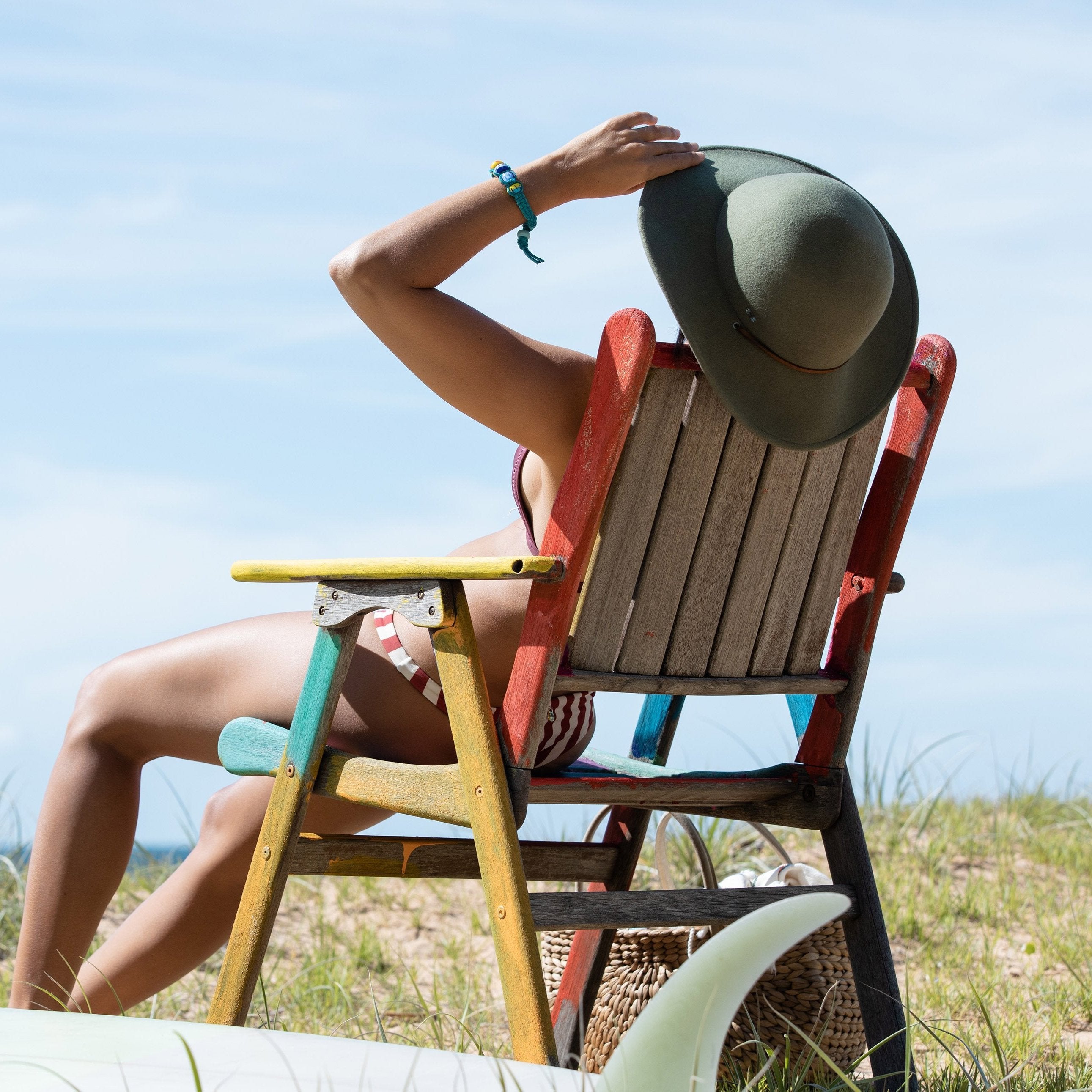 Woman in hat on deckchair at the beach wearing Nalu beads surfers bracelet.