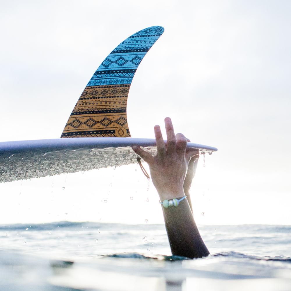 Surfer holding surfboard in the sea holding surfboard with single fin.