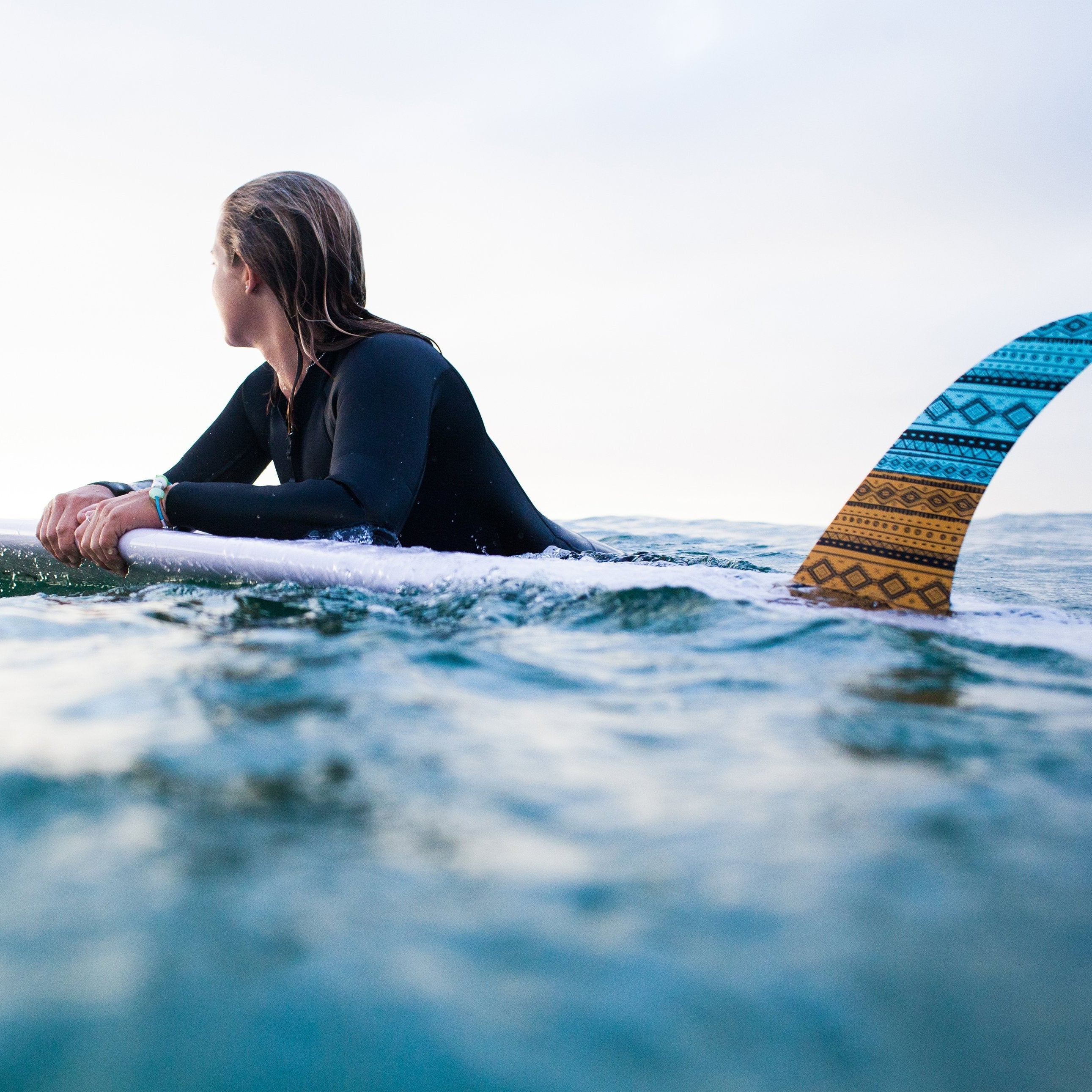 Surfer girl floating on board in sea.