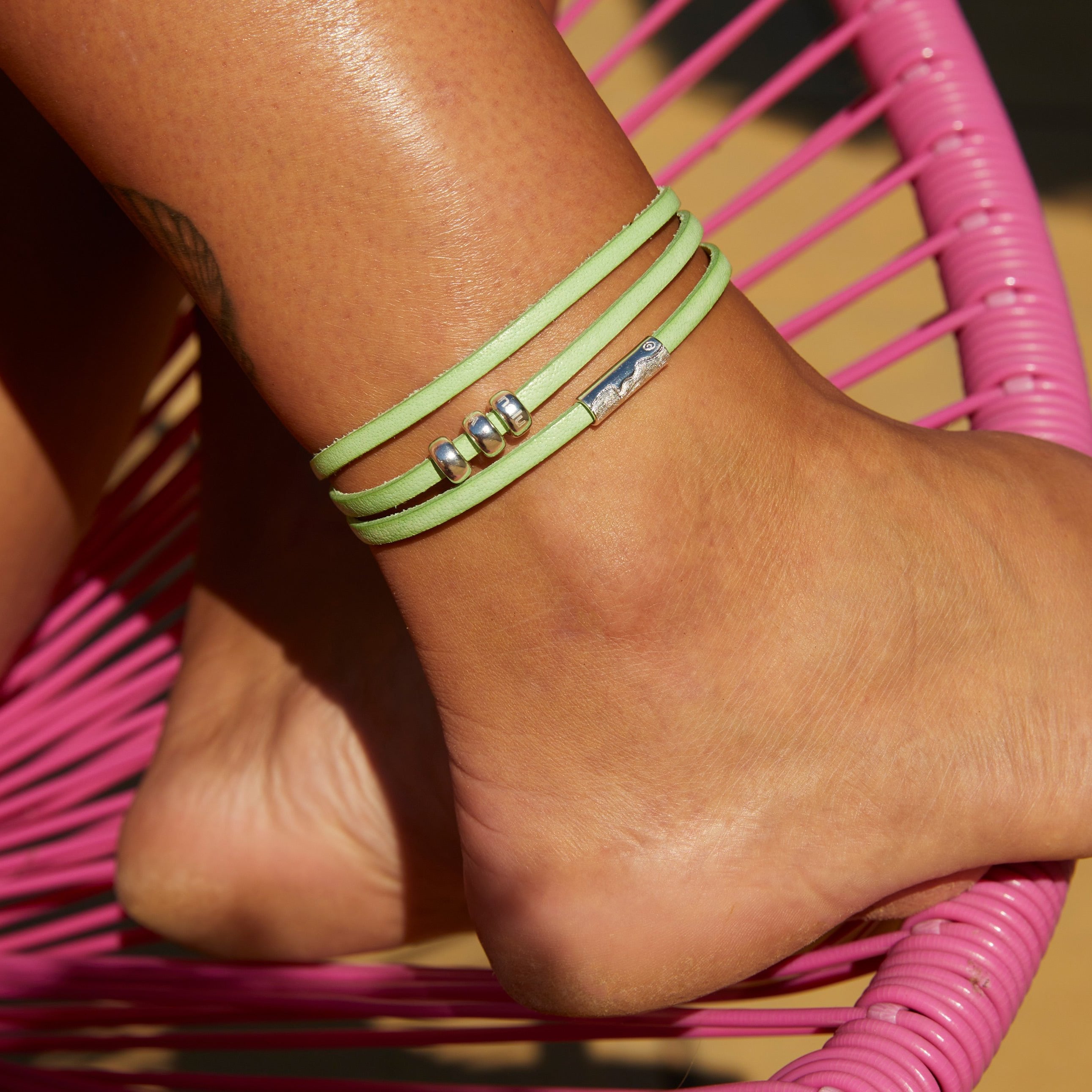 Person waring green silver wrap leather anklet.