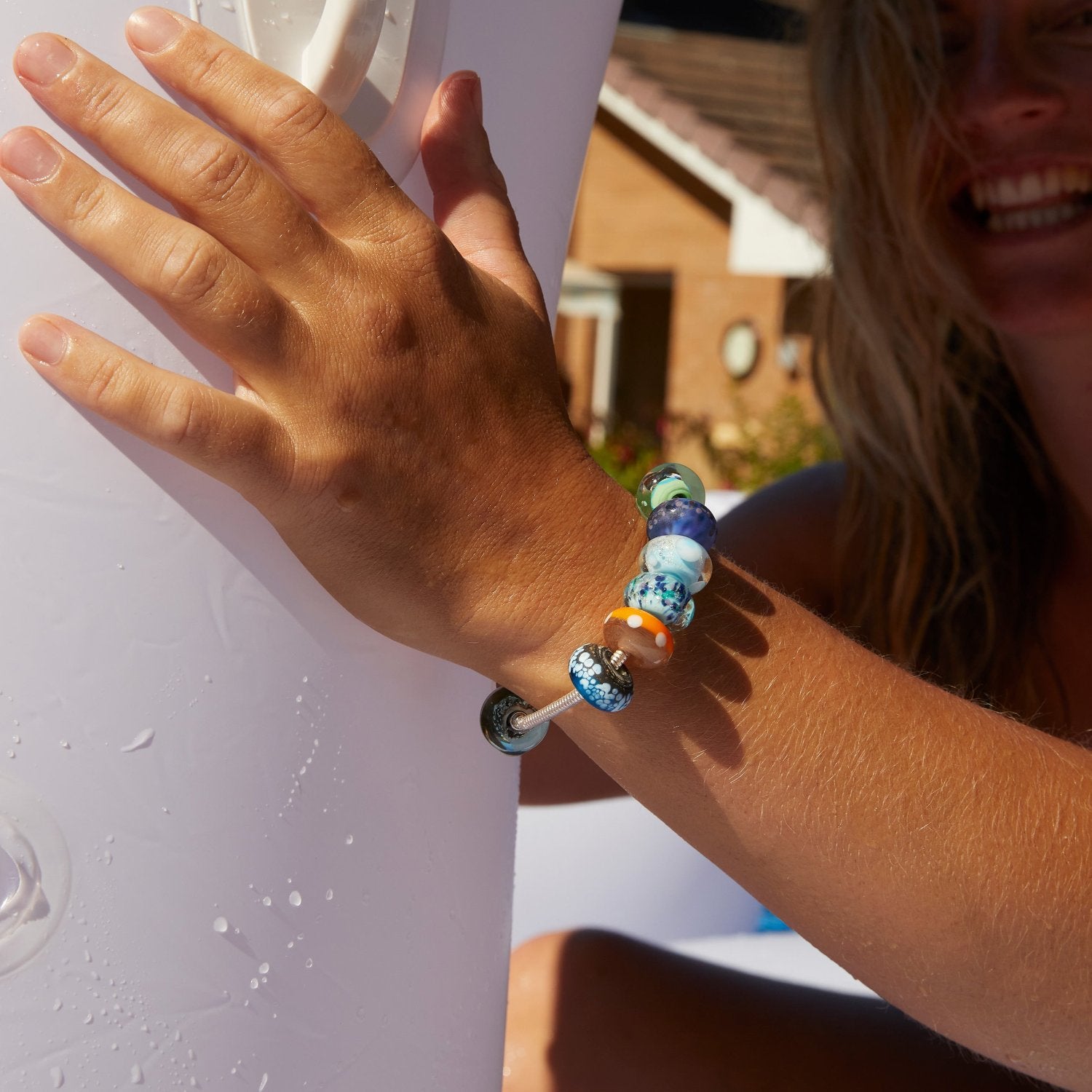 Woman in a pool on inflatable wearing a beaded silver bracelet.