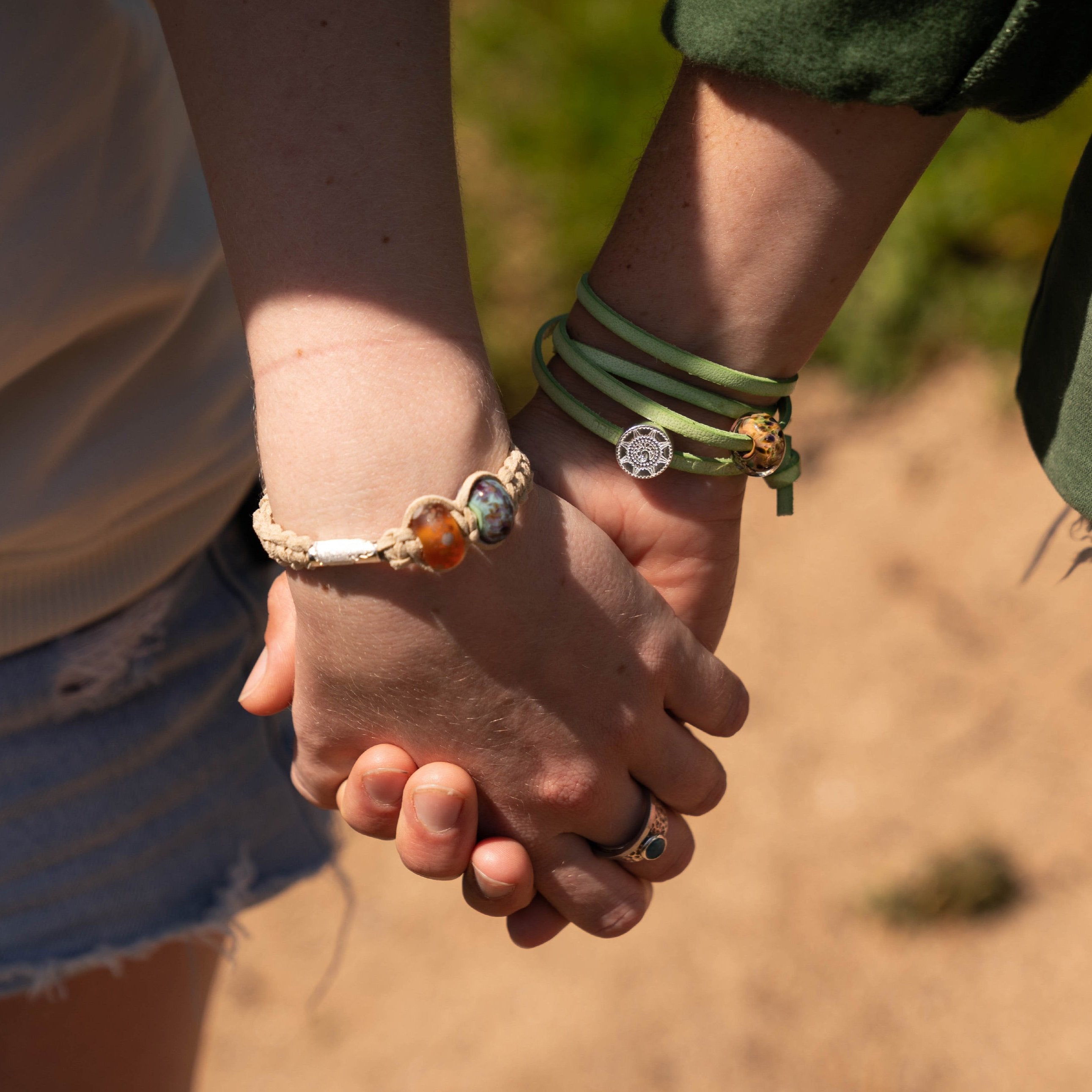 Holding hands wearing beaded silver wrap bracelets.