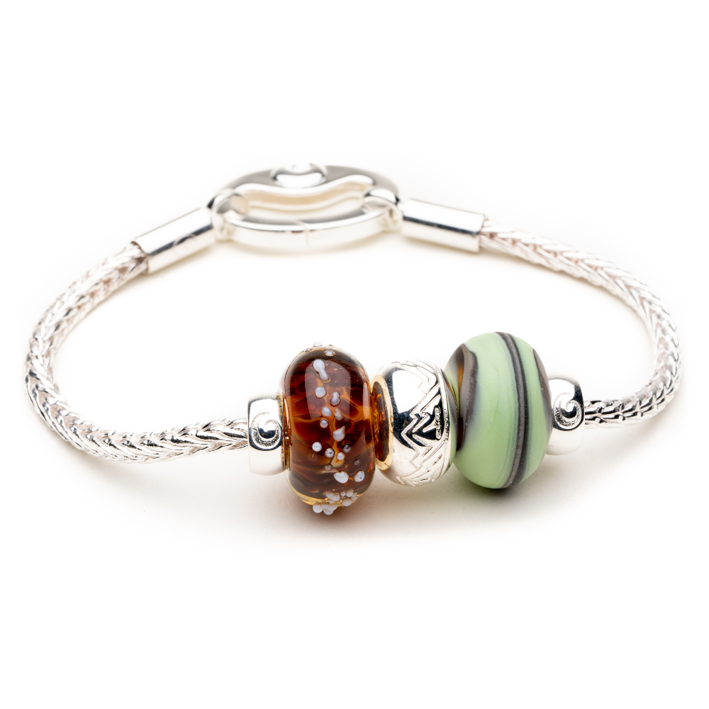 Silver bracelet with brown and green glass and silver beads on it.