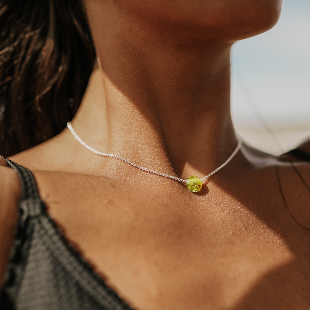 Woman wearing a silver chain necklace with green pebble.