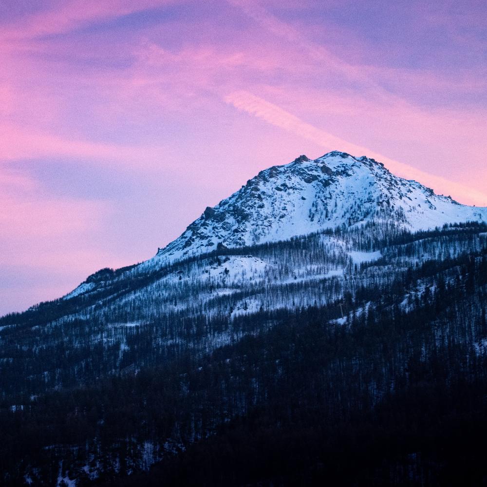 Snowy mountain against a pink sky.