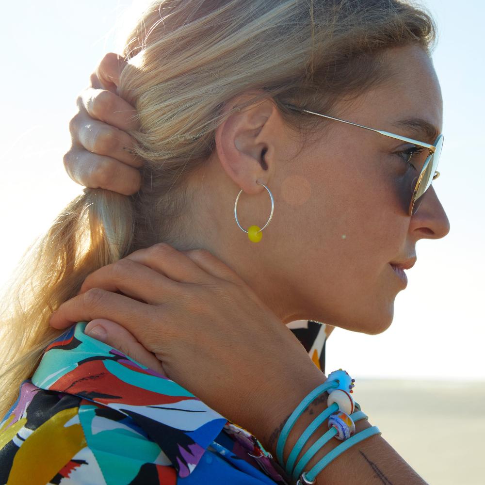 Woman wearing turquoise wrap bracelet with glass beads, on the sunny beach.