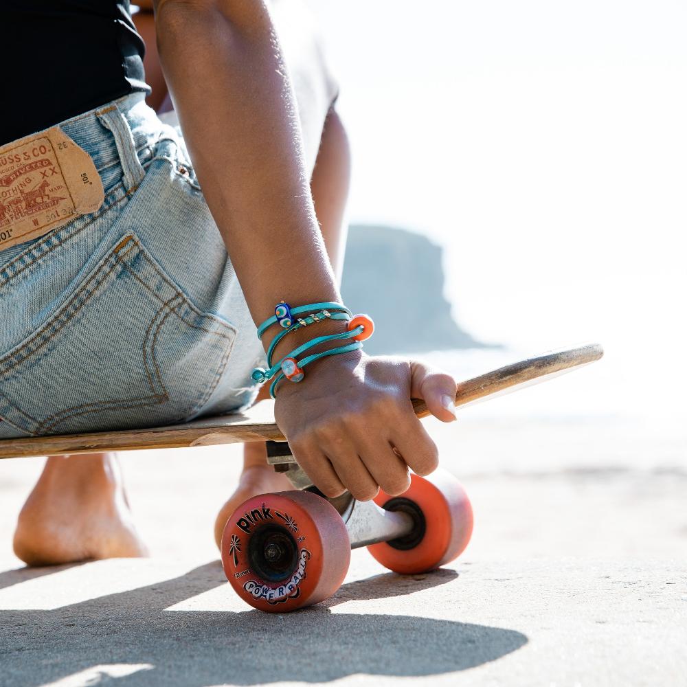 Skater on board wearing denim shorts and blue bracelet.