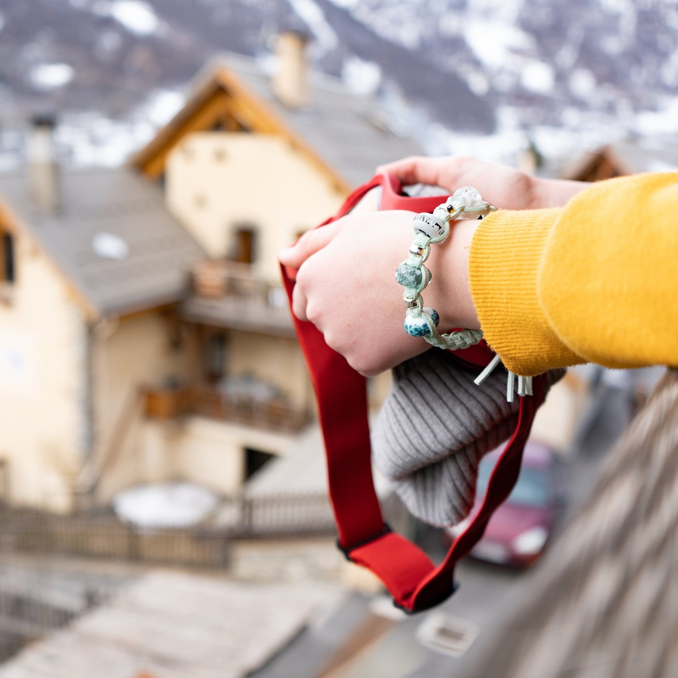 Girl holding ski goggle on the balcony of French snow resort apartment, wearing a Nalu snow bead bracelet.