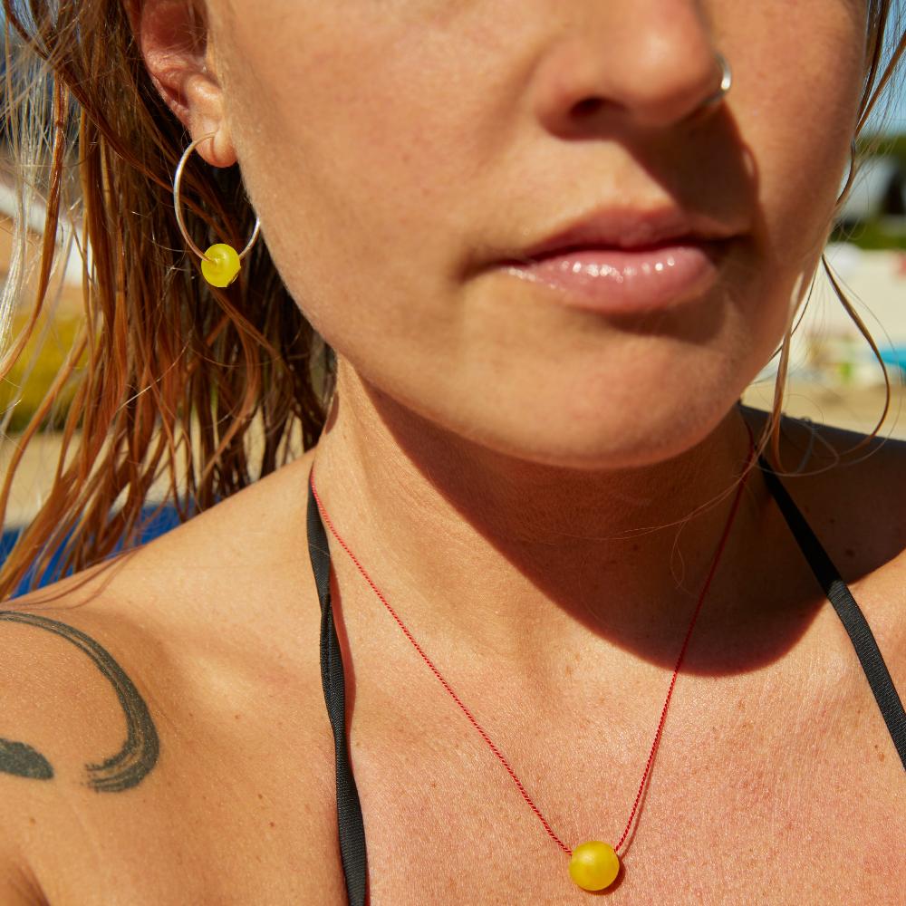 Girl wearing yellow beaded jewellery by the pool.