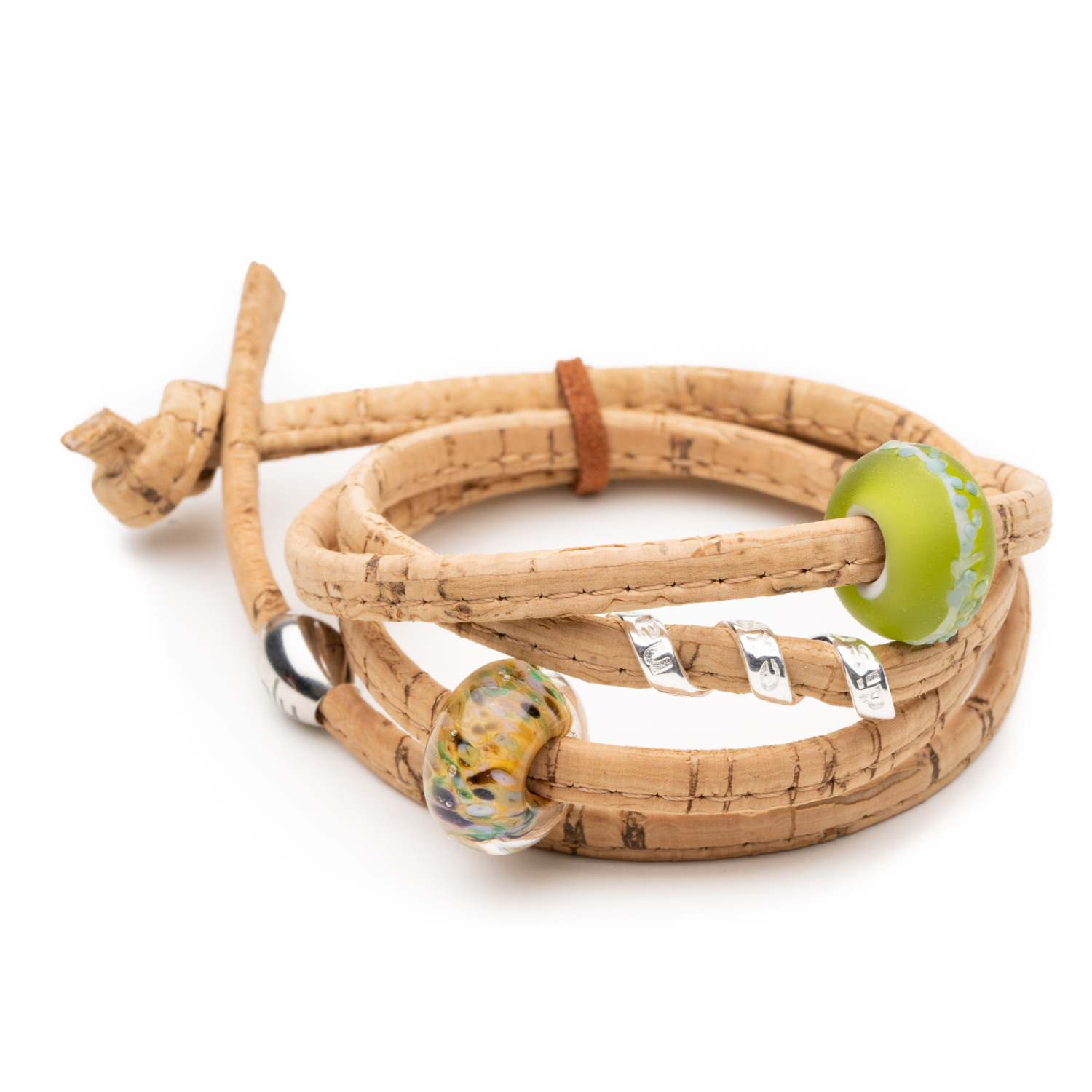 Natural cork bracelet with two glass and a single silver charm worn on it.